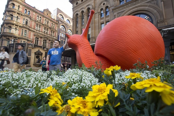 A child poses with a red snail, part of the Snailovation project during the Art & About Festival in Sydney, Australia. Photo Courtesy of: City of Sydney.