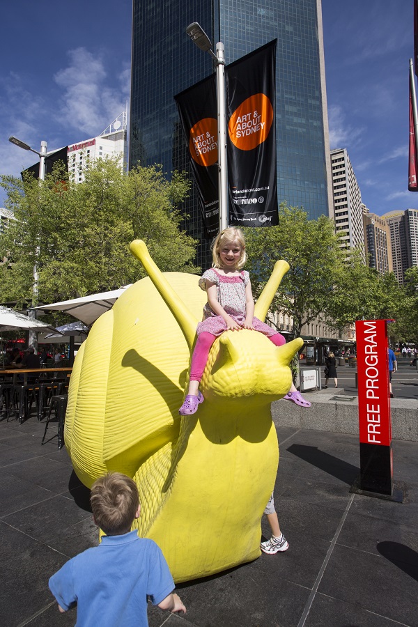A child sits atop a yellow snail, part of the Snailovation project during the Art & About Festival in Sydney, Australia. Photo Courtesy of: City of Sydney.